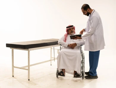 طبيب سعودي يستشير مريض مسن على كرسي متحرك