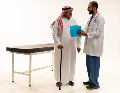 طبيب سعودي يستشير مريضاً مسناً في العيادة