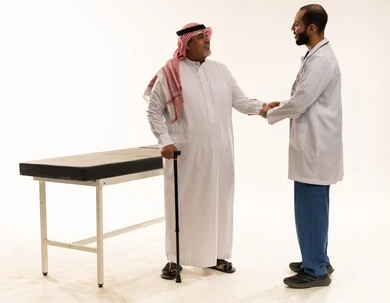 طبيب سعودي يصافح مريض مسن في استوديو طبي