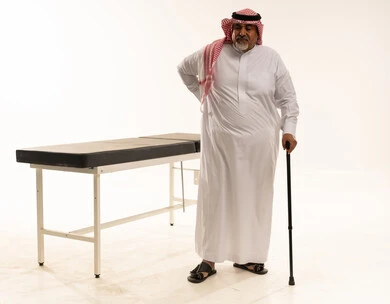 رجل سعودي مسن يعاني من آلام الظهر وعصا المشي