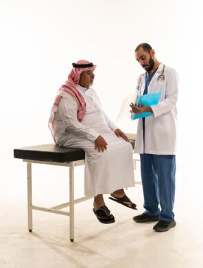 طبيب سعودي يستشير مريضاً مسناً في العيادة
