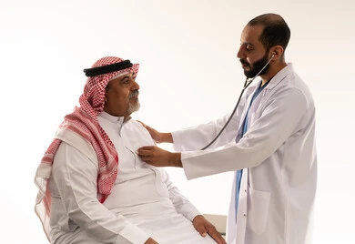طبيب سعودي يفحص مريضاً عربياً مسناً بالسماعة الطبية