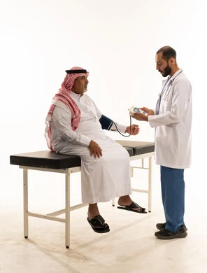 طبيب سعودي يفحص ضغط دم مريض مسن