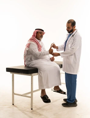 طبيب يفحص مريض سعودي في بيئة طبية