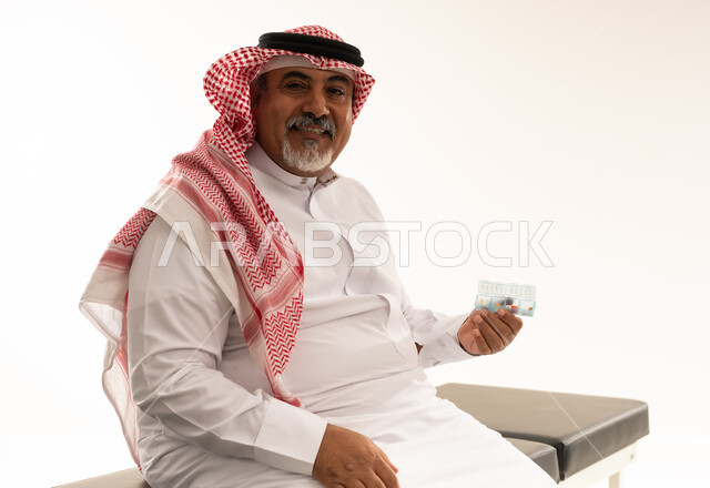 رجل سعودي مسن يحمل منظم حبوب الدواء