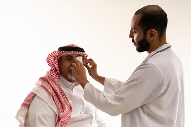 Saudi Doctor Examining Elderly Patient Eye in Studio
