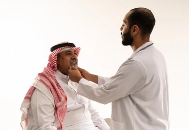 طبيب سعودي يفحص مريضاً مسناً بالزي التقليدي