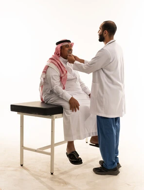 طبيب سعودي يفحص مريضاً مسناً في العيادة