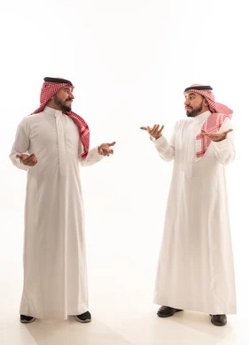 رجلان سعوديان بالزي التقليدي يتحدثان أمام خلفية بيضاء
