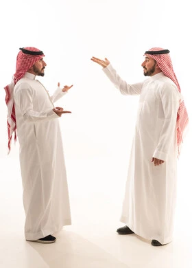 رجال سعوديون بالزي التقليدي يتحدثون على خلفية بيضاء