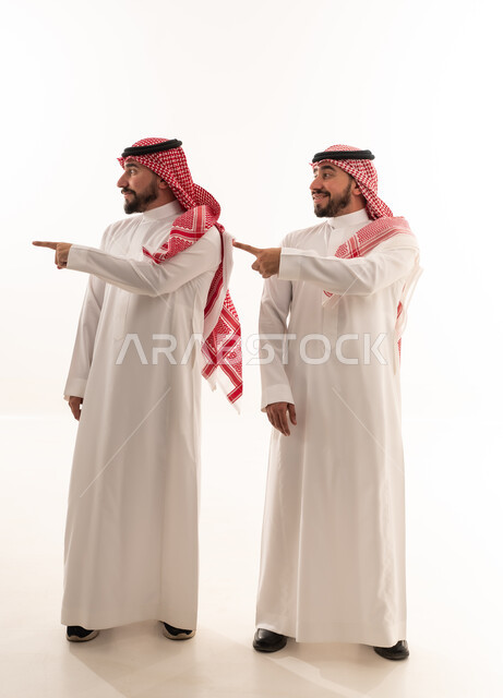 رجلان سعوديان بالزي التقليدي يشيران إلى الجانب