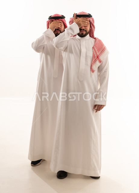 رجلان سعوديان بالزي التقليدي يغطيان أعينهما