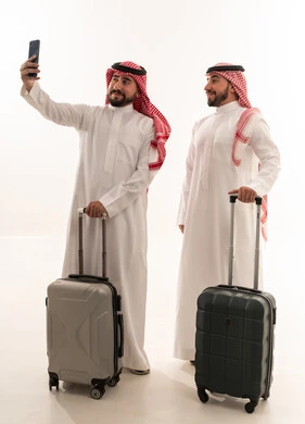 رجال سعوديون مع حقائب سفر يلتقطون صورة سيلفي