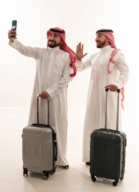 رجال سعوديين مع حقائب سفر يلتقطون صورة سيلفي