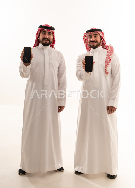 رجال سعوديون بالزي التقليدي يحملون هواتف ذكية