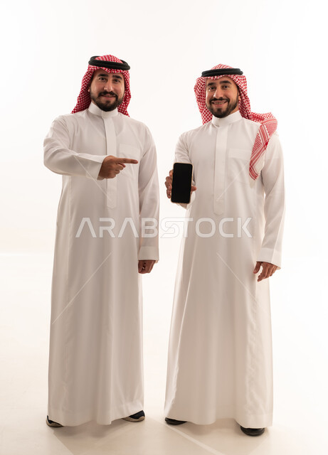 رجال سعوديون بالثوب التقليدي يحملون هاتف ذكي
