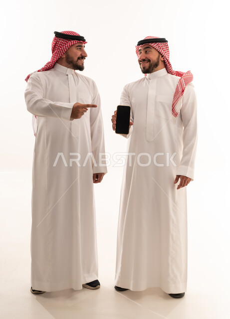 Saudi Men in Traditional Thobes Holding Smartphone