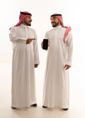 رجال سعوديون بالزي التقليدي يحملون هاتف ذكي