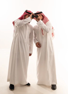 رجال سعوديون بالزي التقليدي ينظرون عبر المنظار