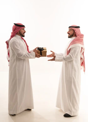 رجال سعوديون يتبادلون هدية على خلفية بيضاء