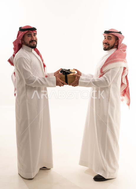 رجال سعوديون بالزي التقليدي يتبادلون صندوق هدايا