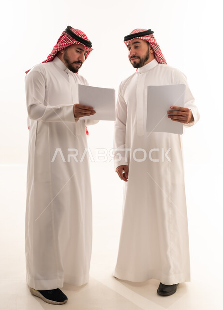 رجال أعمال سعوديون يراجعون مستندات في الاستوديو