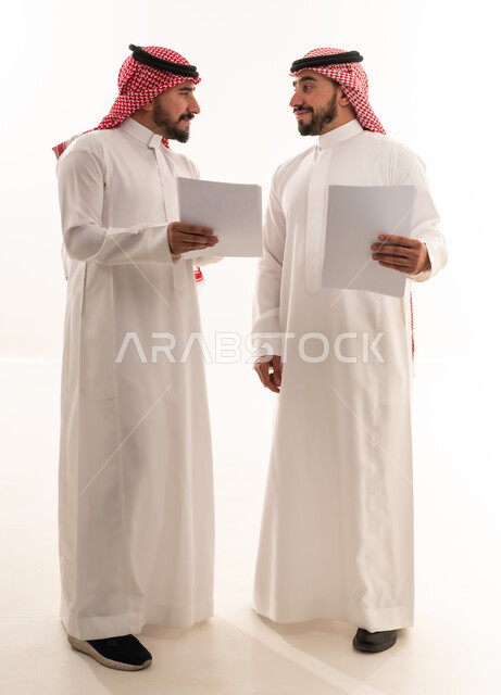 رجال أعمال سعوديون يحملون وثائق ورقية بخلفية بيضاء