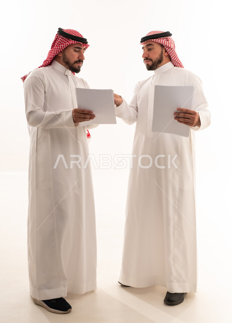رجال أعمال سعوديون يراجعون مستندات ورقية معاً
