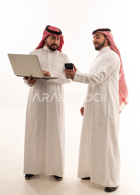 رجال سعوديون يستخدمون لابتوب وهاتف ذكي بخلفية بيضاء