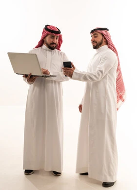 رجال سعوديون يستخدمون لابتوب وهاتف ذكي بخلفية بيضاء