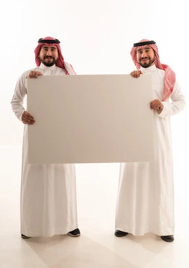 رجلان سعوديان يحملان لوحة بيضاء فارغة في استوديو