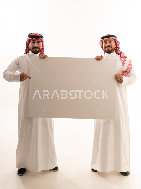 رجال سعوديين يحملون لوحة إعلانية بيضاء فارغة