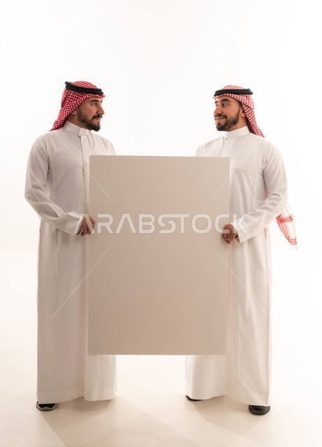 رجلان سعوديان يحملان لوحة بيضاء فارغة في الاستوديو