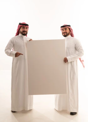 رجال سعوديون يحملون لوحة إعلانية بيضاء فارغة في الاستوديو
