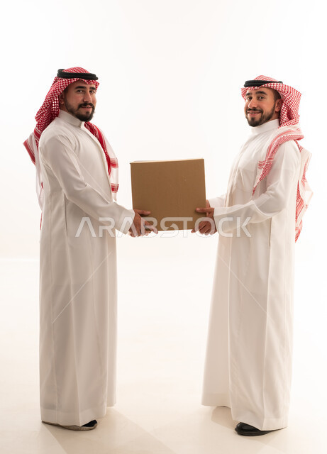 رجال سعوديون يحملون صندوق توصيل كرتوني