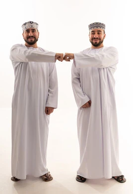 رجلان عمانيان بالزي التقليدي يتبادلان التحية بقبضة اليد