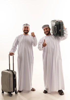 رجال عمانيون مع حقائب سفر باللباس التقليدي