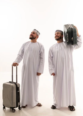 رجلان عُمانيان بملابس تقليدية مع حقائب سفر في الاستوديو