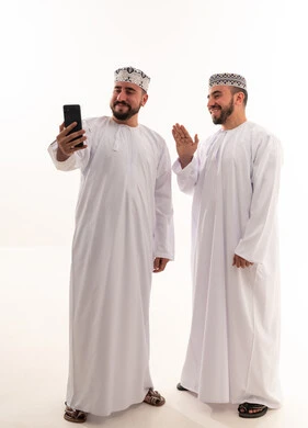 رجال عمانيون بالزي التقليدي يستخدمون الهاتف الذكي