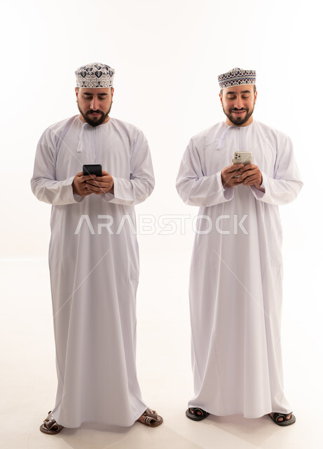 رجال عمانيون بالزي التقليدي يستخدمون الهواتف الذكية