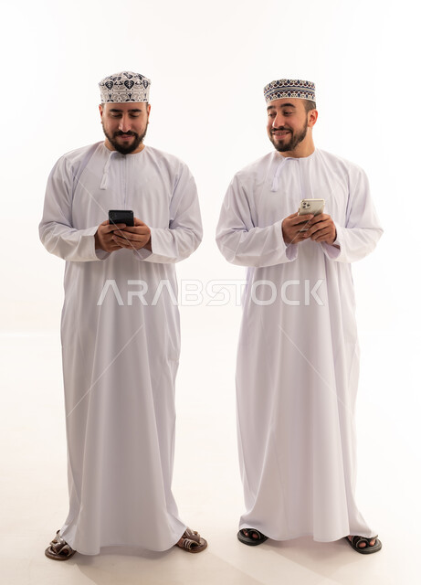 Omani Men in Traditional Dress Using Smartphones