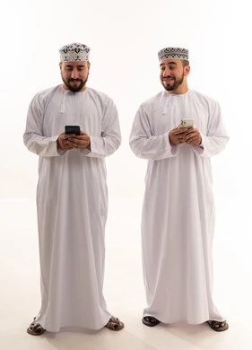 Omani Men in Traditional Dress Using Smartphones
