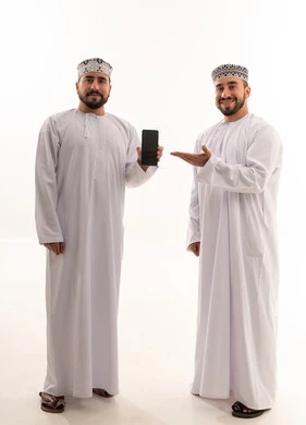 رجلان عمانيان بالزي التقليدي يحملان هاتفاً ذكياً