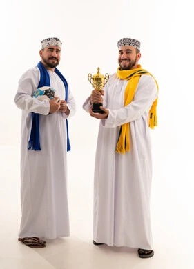 رجال عمانيون يحملون كرة قدم وكأس البطولة الذهبي