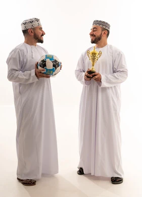رجال عمانيون مع كرة قدم وكأس فوز