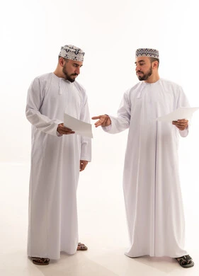 Omani Men in Traditional Dress Discussing Business Papers