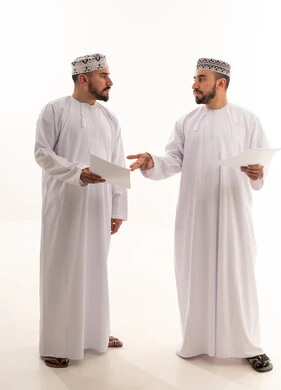 Omani Men in Traditional Dress Discussing Documents