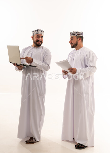 رجال عمانيون مع حاسوب محمول ومستندات في استوديو
