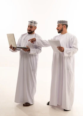 Two Omani Men Using Laptop for Business Discussion