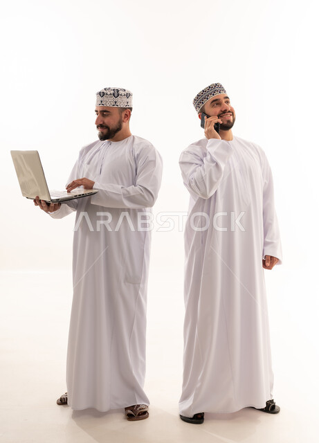 Omani Men Using Laptop and Phone in Traditional Dress